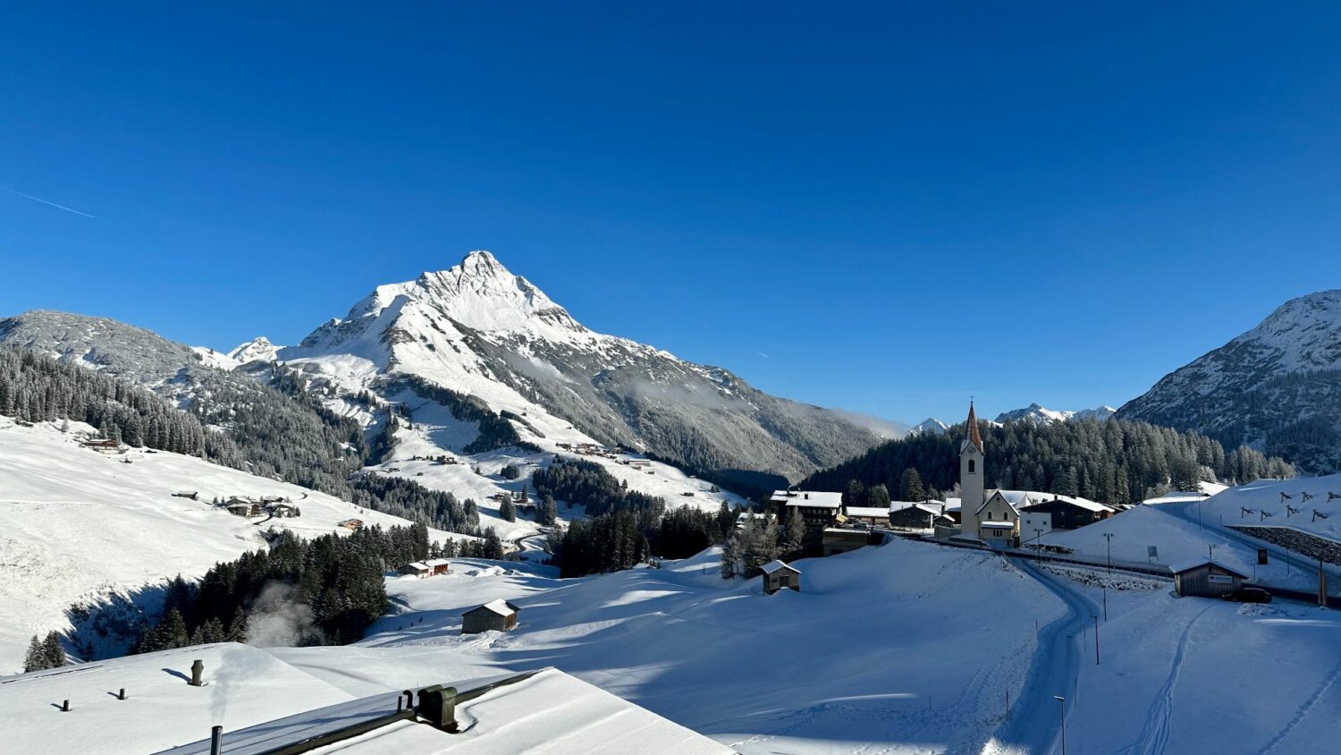 BBerg Biberkopf und Warth mit Kirche am Arlberg im Winter in Österreich