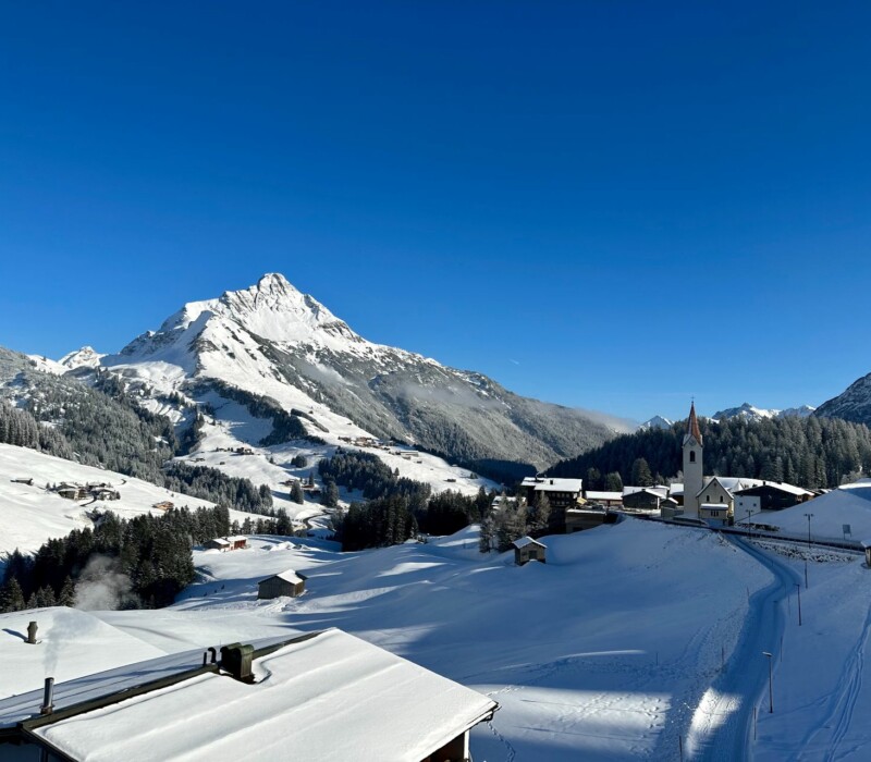 BBerg Biberkopf und Warth mit Kirche am Arlberg im Winter in Österreich